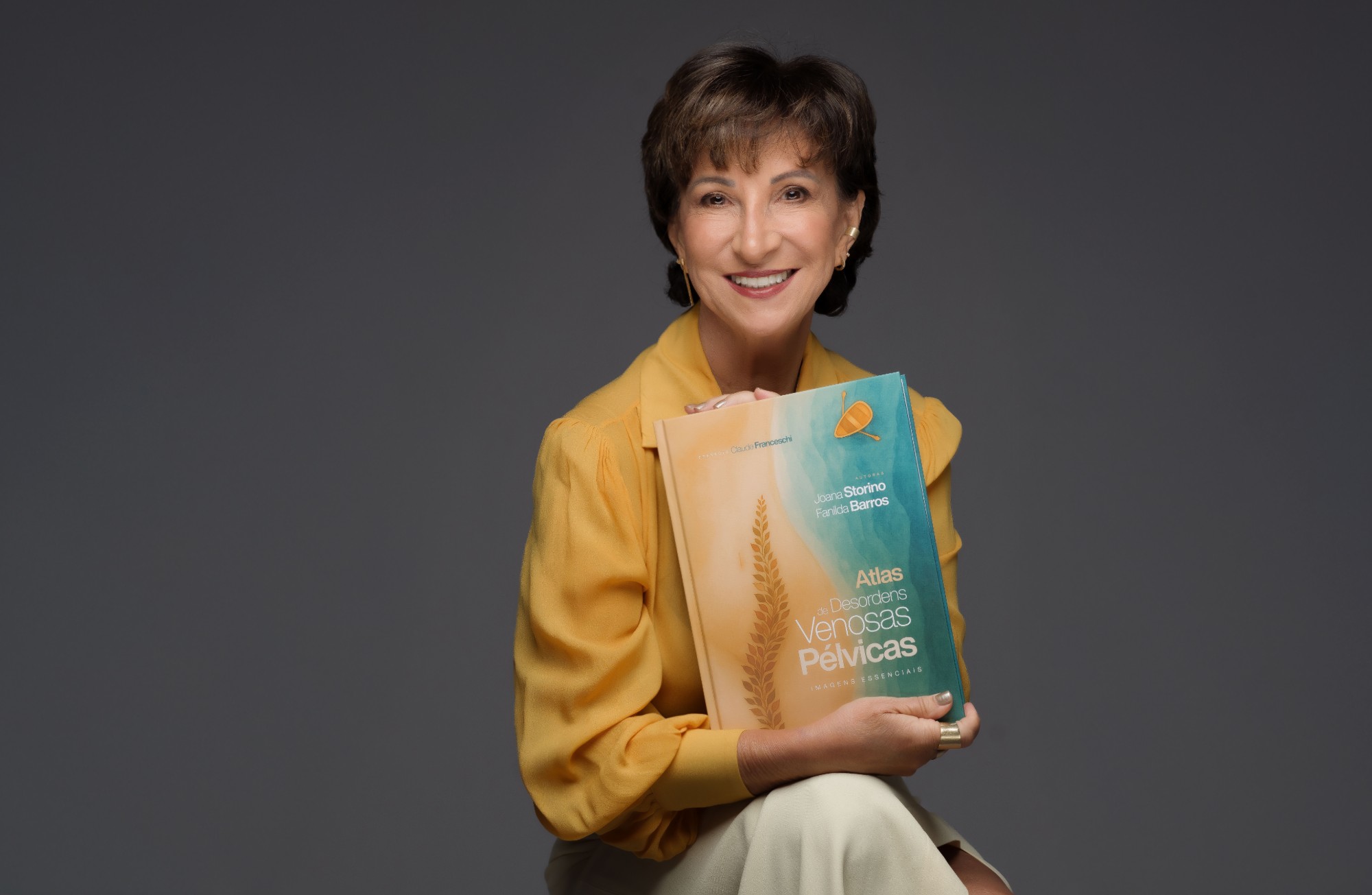 Dra. Fanilda Barros segurando o livro Atlas de Desordens Venosas Pélvicas: imagens essenciais